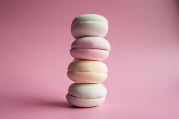 A photo of zephyr, zephyr, marshmallow, soft confectionery, candy on a pink background.