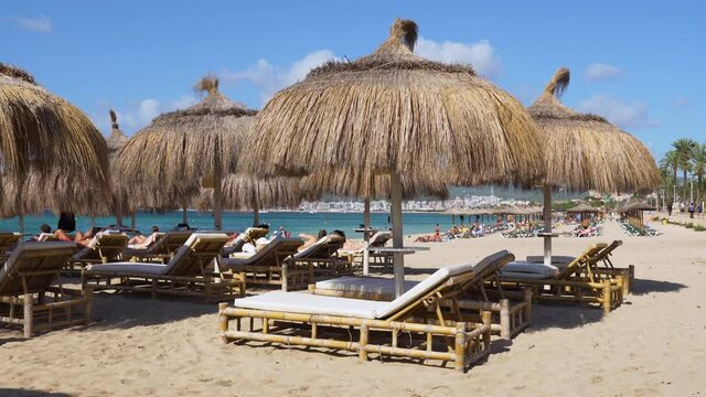 Tourists sunbathing and Beach Straw umbrellas on the beach of Palma de Mallorca - Spain