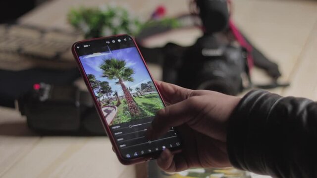 Hands Holding Smartphone editing photo using lightroom