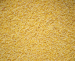 yellow round grains are spread on a flat surface. polished millet. texture and details. traditional dishes. close-up