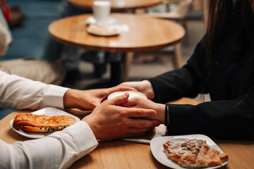 Romantic couple man and woman hold each other's hands in a cafe. There are pastries and coffee on the table.