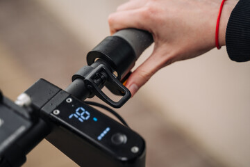 Female hand holds a finger on the throttle of the electric scooter by pushing it.