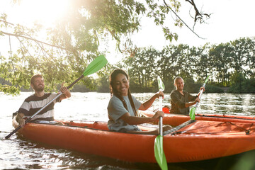 Happy couple kayaking on the river surrounded by trees, enjoying adventurous experience