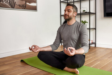 Middle-aged Caucasian man meditate practice yoga at home