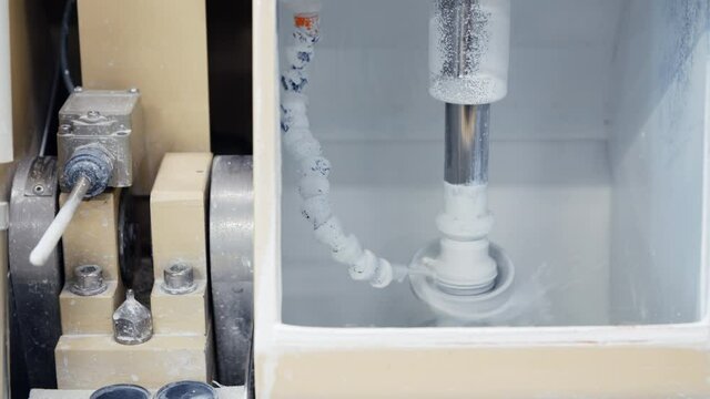 Close-up lens and glass details polishing machine at factory. Mechanical glass polishing with special white liquid. Lens manufacturing