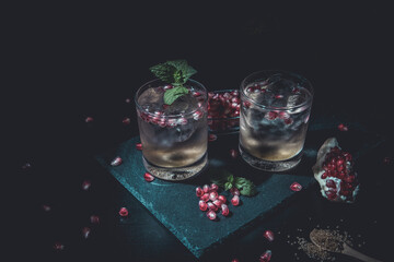 Fototapeta na wymiar two moody drinks on a black background with mint and pomegranate