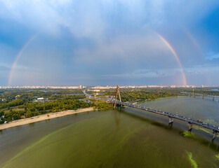 Fototapeta na wymiar Rainbow over the North Bridge in Kiev. Green algae bloom in the water of the Dnieper River. Aerial drone view.