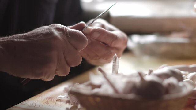 male hands with a knife peels a clove of garlic sitting at the table. close-up view.