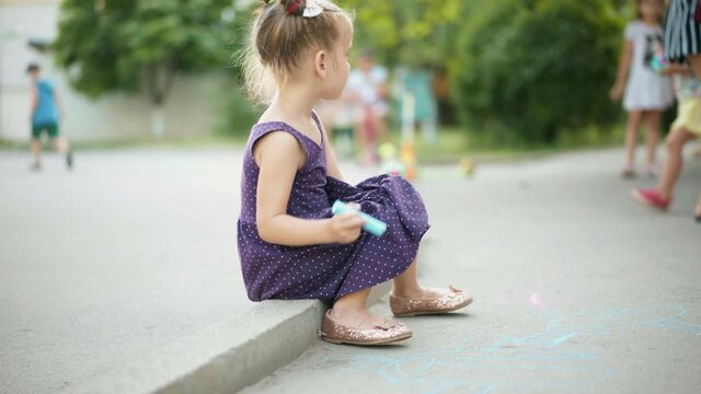 Child Drawing Chalk Asphalt Road Summer Day. Caucasian Little Girl 4-5 Years Chalking Outdoors Pavement Happy Childhood Leisure Game For Kid