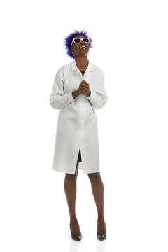 Happy Black Woman In A White Lab Coat Is Standing With Holding Hands And Looking Up. Full Length, Isolated.