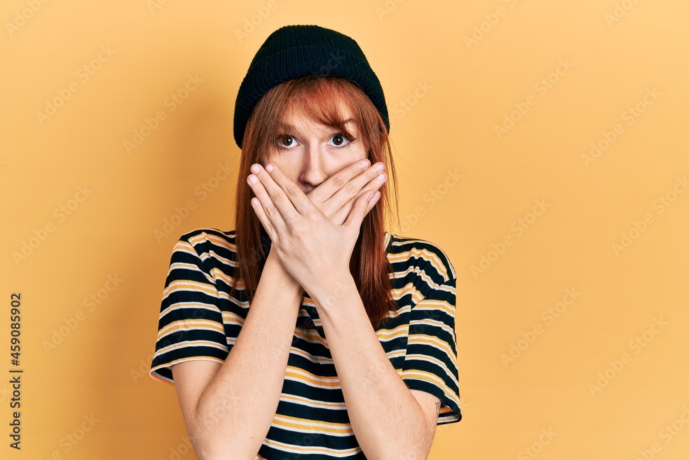 Sticker Redhead young woman wearing wool cap shocked covering mouth with hands for mistake. secret concept.