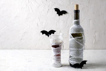 Glass and Bottle of cocktail decorated as mummy. Drink for a halloween party