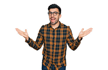 Naklejka premium Hispanic man with beard wearing casual clothes and glasses celebrating victory with happy smile and winner expression with raised hands