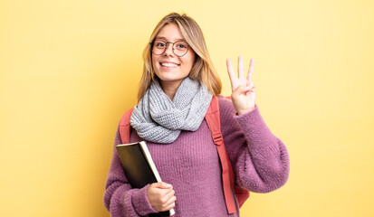 pretty blonde girl smiling and looking friendly, showing number three. student concept