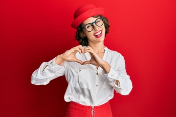 Young brunette woman wearing stewardess style and glasses smiling in love showing heart symbol and shape with hands. romantic concept.