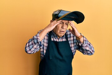 Handsome senior man with grey hair wearing welding protection mask with hand on head for pain in head because stress. suffering migraine.
