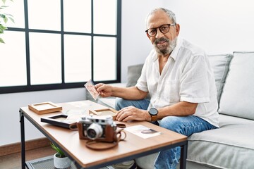 Senior grey-haired man smiling confident looking picture at home