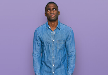 Obraz premium Young african american man wearing casual clothes smiling looking to the side and staring away thinking.