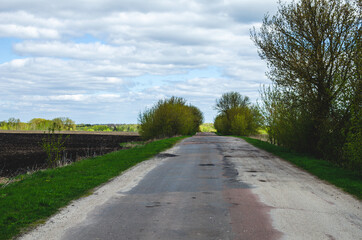 An asphalt road stretching into the distance beyond the horizon. Road destroyed after winter. A hole in the road