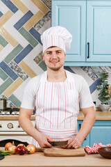 A beautiful man preparing a salad at home in the kitchen. Cooking.