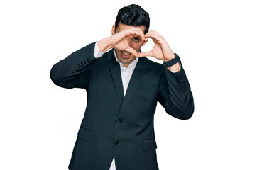 Handsome hispanic man wearing business clothes doing heart shape with hand and fingers smiling looking through sign