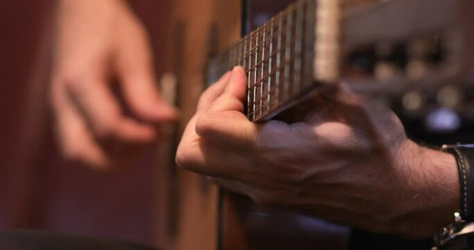 Musician plays classical acoustic guitar with nylon strings, close-up focus on musician's left hand on fingerboard