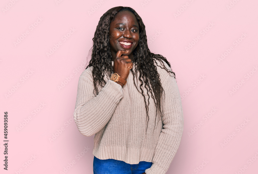 Sticker Young african woman wearing wool winter sweater looking confident at the camera smiling with crossed arms and hand raised on chin. thinking positive.