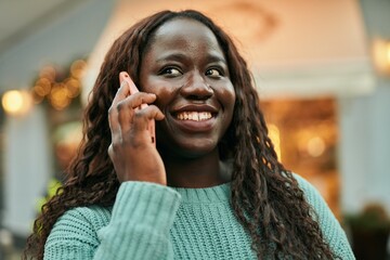 Young african woman smiling happy speaking on the phone at the city