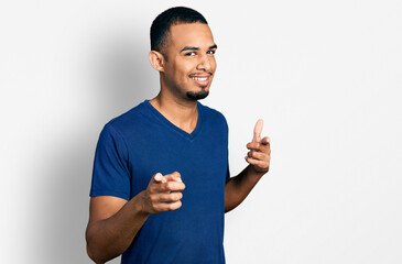 Young african american man wearing casual t shirt pointing fingers to camera with happy and funny face. good energy and vibes.