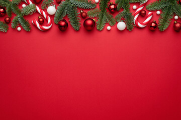 Red background with Christmas decorations of fir branches and Christmas balls