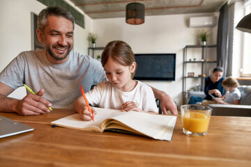 Smiling father help small daughter with school homework