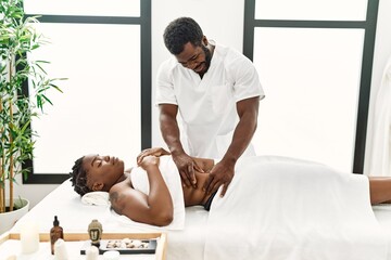Young physiotherapist man giving abdominal massage to african american woman at the clinic - Powered by Adobe