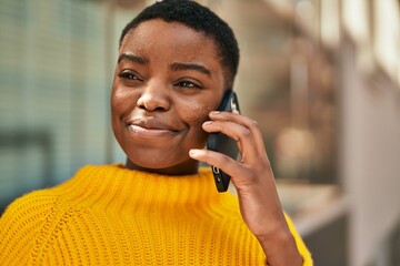 Young african american woman smiling happy talking on the smartphone at the city