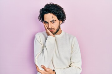Handsome hispanic man wearing casual white sweater thinking looking tired and bored with depression problems with crossed arms.