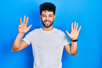 Young arab man with beard wearing casual white t shirt showing and pointing up with fingers number...