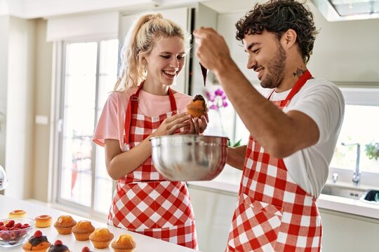 Young couple smiling happy cooking sweets at kitchen.