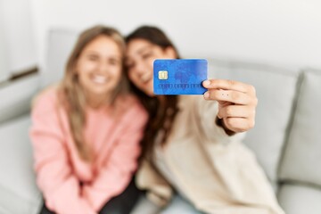 Young couple smiling happy holding credit card at home.