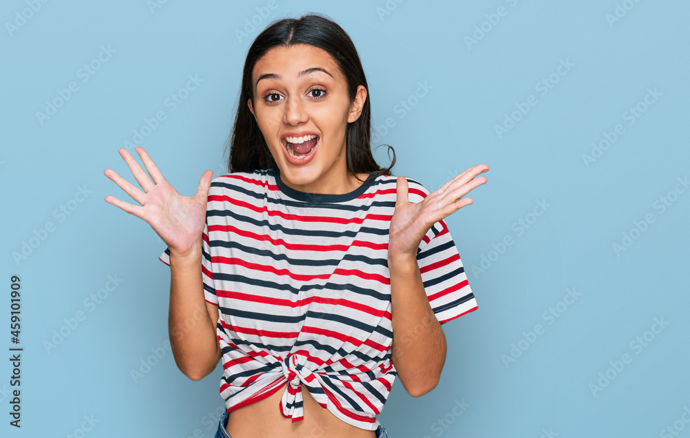 Wall mural young hispanic girl wearing casual clothes celebrating crazy and amazed for success with arms raised