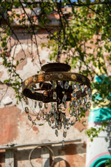 an old rusty chandelier with glass pendants hangs on a tree branch