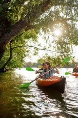 Adventurous friends paddling together on the river surrounded by trees at spring or summer