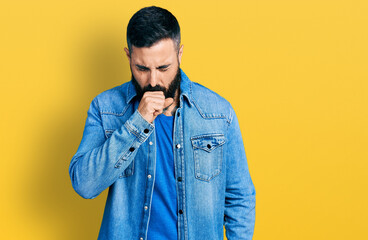 Hispanic man with beard wearing casual denim jacket feeling unwell and coughing as symptom for cold or bronchitis. health care concept.