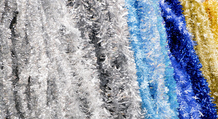 Shining tinsel garland background. Silver, blue and gold iridescent tinsel. Copy space.