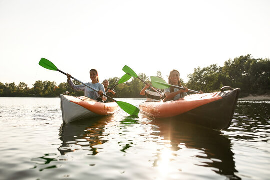 Friends kayaking together in river at spring or summer, spending time together outdoors - Powered by Adobe