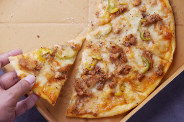 top view of man hand picking slice of pizza from a plate 