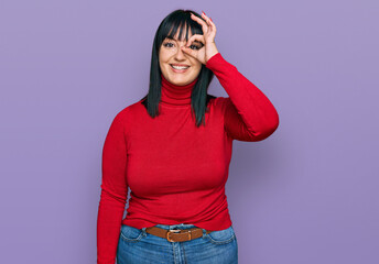 Young hispanic woman wearing casual clothes doing ok gesture with hand smiling, eye looking through fingers with happy face.