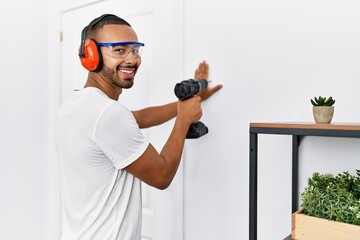 Young hispanic man smiling confident using drill at home