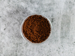 Close shot of coffee powder in glass bowl with defocused background.