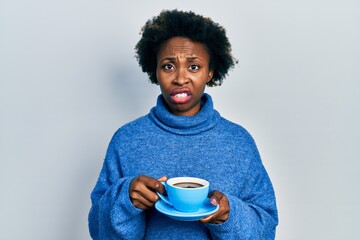 Young african american woman drinking a cup of coffee clueless and confused expression. doubt...