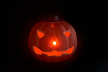 A glowing carved pumpkin in a black background - halloween concept