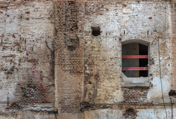 Fototapeta na wymiar Broken red brick wall and damaged plaster on the background